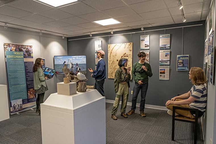 Students with work in the Chesapeake Semester exhibit talk in the MuSE: A Community Museum space as installation is completed.